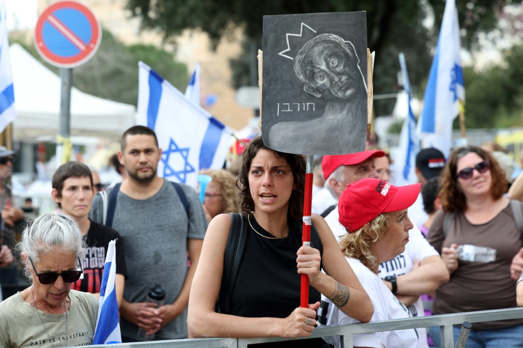 امرأة تحمل لافتة كتب عليها "دمار" باللغة العبرية مع رسم يصوّر رئيس الوزراء بنيامين نتانياهو خلال تظاهرة ضدّ الحكومة أمام الكنيست القدس في الثاني من نيسان/أبريل 2024 (أ ف ب)   