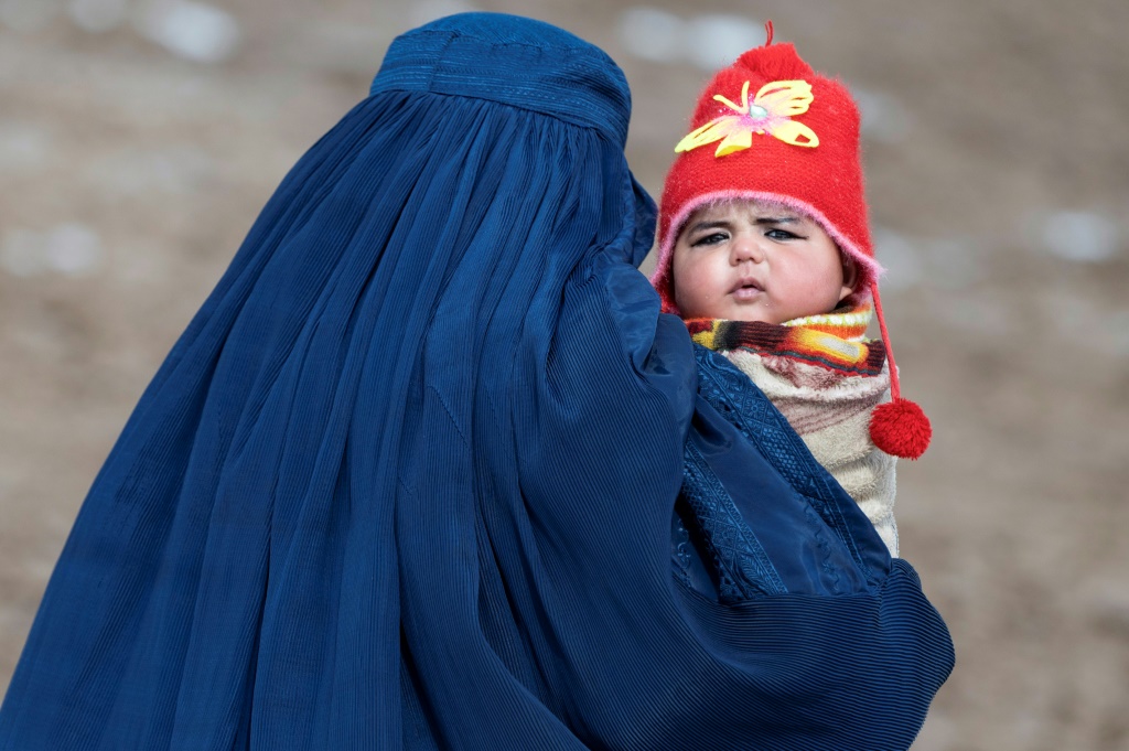    تُظهر هذه الصورة التي تم التقاطها في 25 شباط/فبراير 2024 امرأة أفغانية ترتدي البرقع تحمل طفلاً إلى مركز صحي لتطعيمه في اطار برنامج "التطعيم التوعوي"، وهو عمل تحصين روتيني في قرية آب باريك في منطقة أرغو في مقاطعة بدخشان. (أ ف ب)   