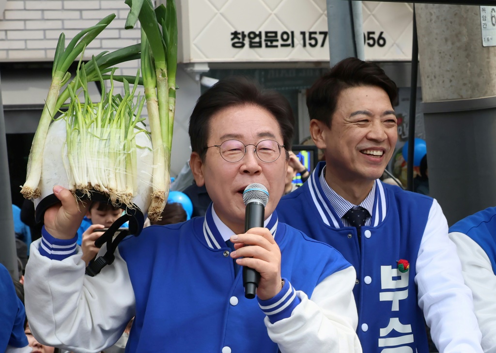 زعيم الحزب الديمقراطي المعارض الرئيسي في كوريا الجنوبية لي جاي ميونغ يحمل خوذة مزينة بالبصل الأخضر خلال إحدى فعاليات الحملة الانتخابية وهو يوضح نقطة حول ارتفاع الأسعار (ا ف ب)