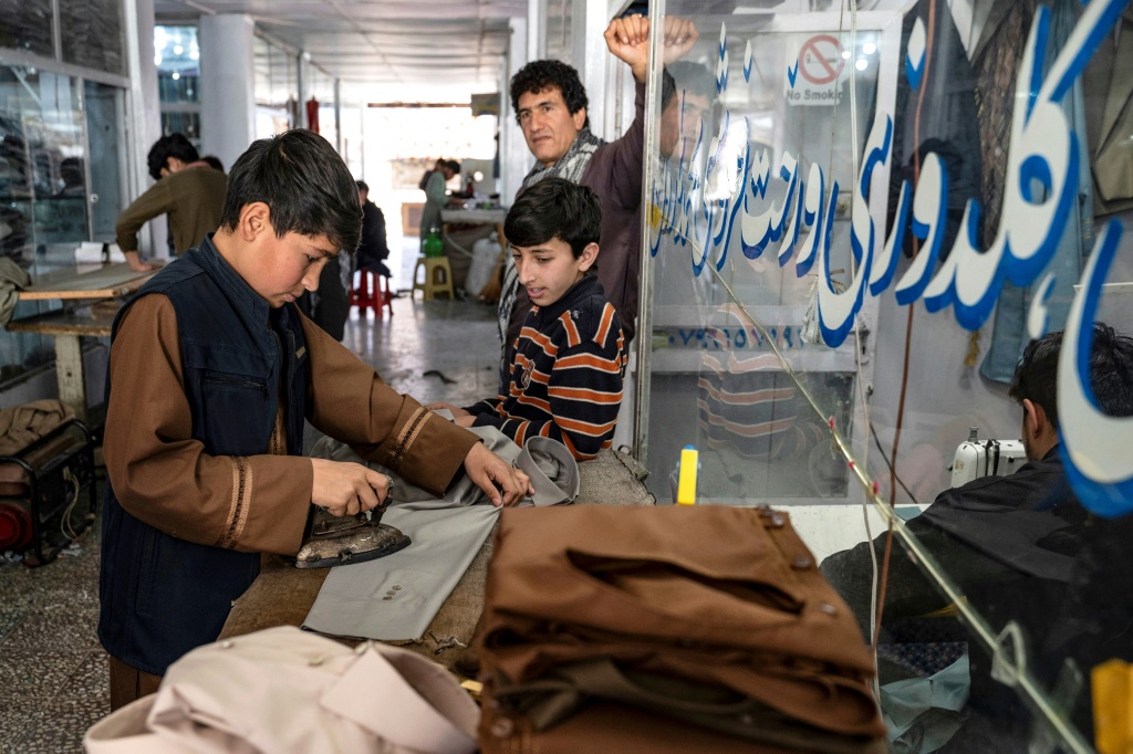 شاب أفغاني يكوي الملابس قبل عيد الفطر في ورشة خياطة في كابول في 7 نيسان/أبريل 2024 (أ ف ب)   