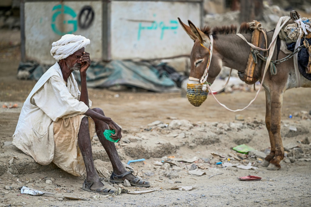 رجل مسن ينتظر إعادة ملء خزان المياه الذي يجره حمار في ظل أزمة المياه في بورتسودان بولاية البحر الأحمر في السودان الذي مزقته الحرب، في 9 نيسان/أبريل 2024 (ا ف ب)