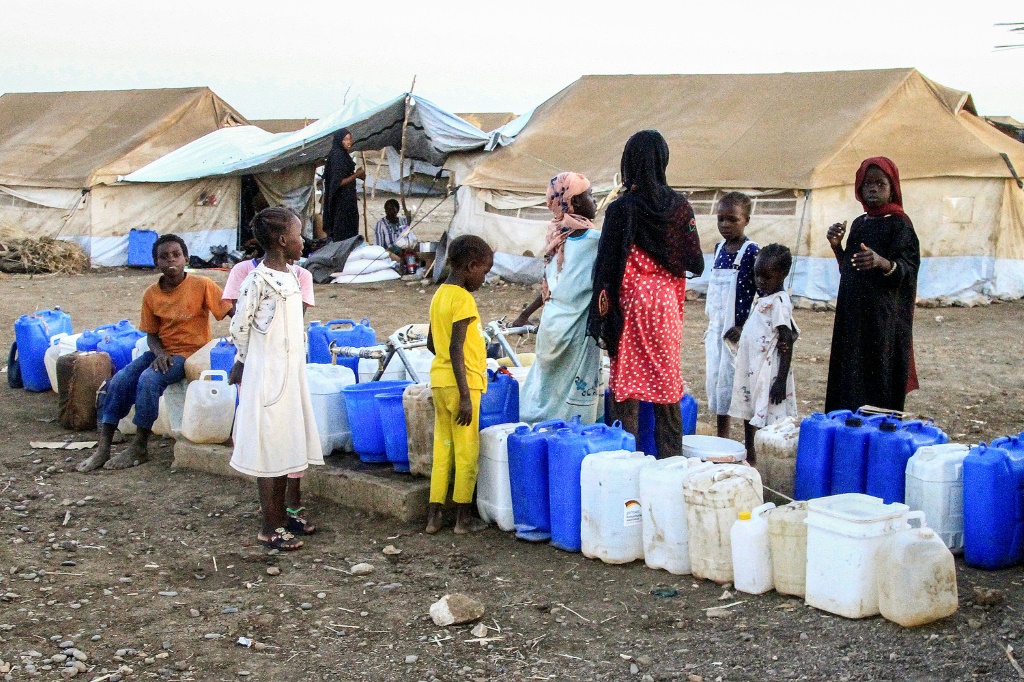 نساء وأطفال يصطفون للحصول على المياه في مخيم هوري للنازحين جنوب القضارف في شرق السودان، في 29 مارس/آذار (ا ف ب)