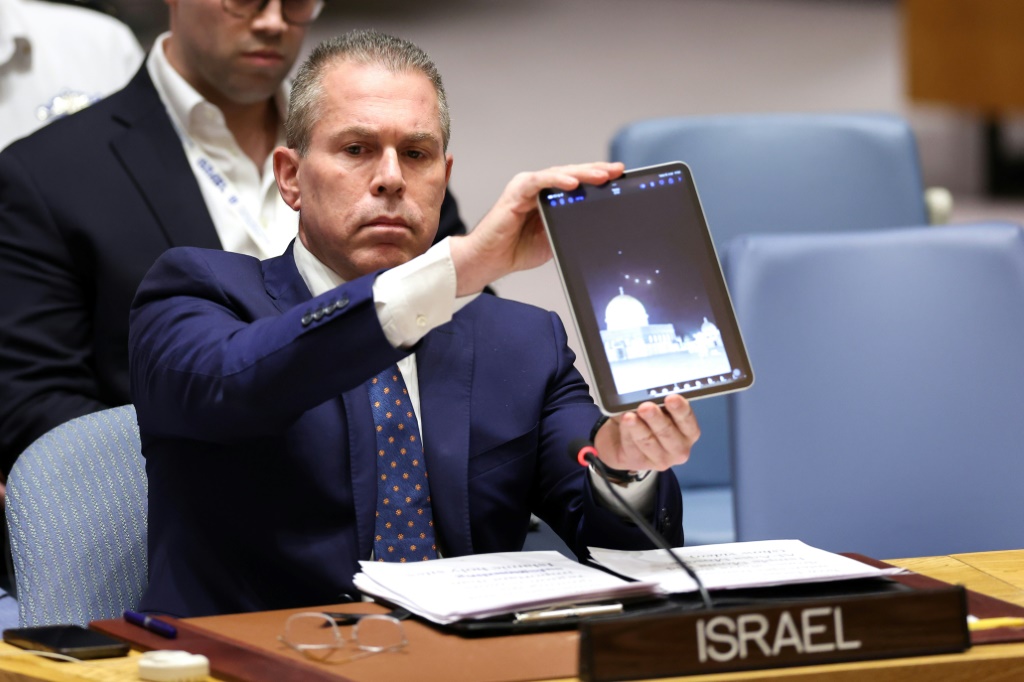    السفير الإسرائيلي لدى الأمم المتحدة جلعاد إردان يعرض مقطع فيديو لطائرات مسيرة وصواريخ تتجه نحو إسرائيل خلال اجتماع لمجلس الأمن التابع للأمم المتحدة حول الوضع في الشرق الأوسط في مقر الأمم المتحدة في مدينة نيويورك، 14 أبريل، 2024. (أ ف ب)   
