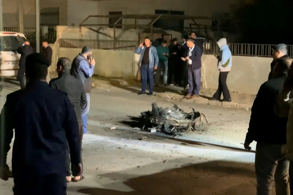 متفرجون أردنيون ورجال أمن ينظرون إلى حطام صاروخ اعترضته القوات الأردنية فوق عمان وسط هجوم إيراني غير مسبوق بطائرة بدون طيار وصاروخ على إسرائيل في الساعات الأولى من يوم 14 أبريل 2024 (أ ف ب)   