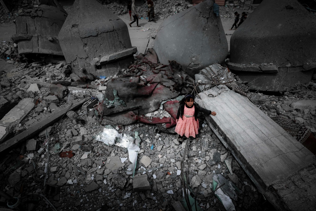 فتاة فلسطينية وسط أنقاض مسجد الفاروق الذي دمره قصف إسرائيلي على مدينة رفح جنوب قطاع غزة، 22 مارس 2024 (ا ف ب)
