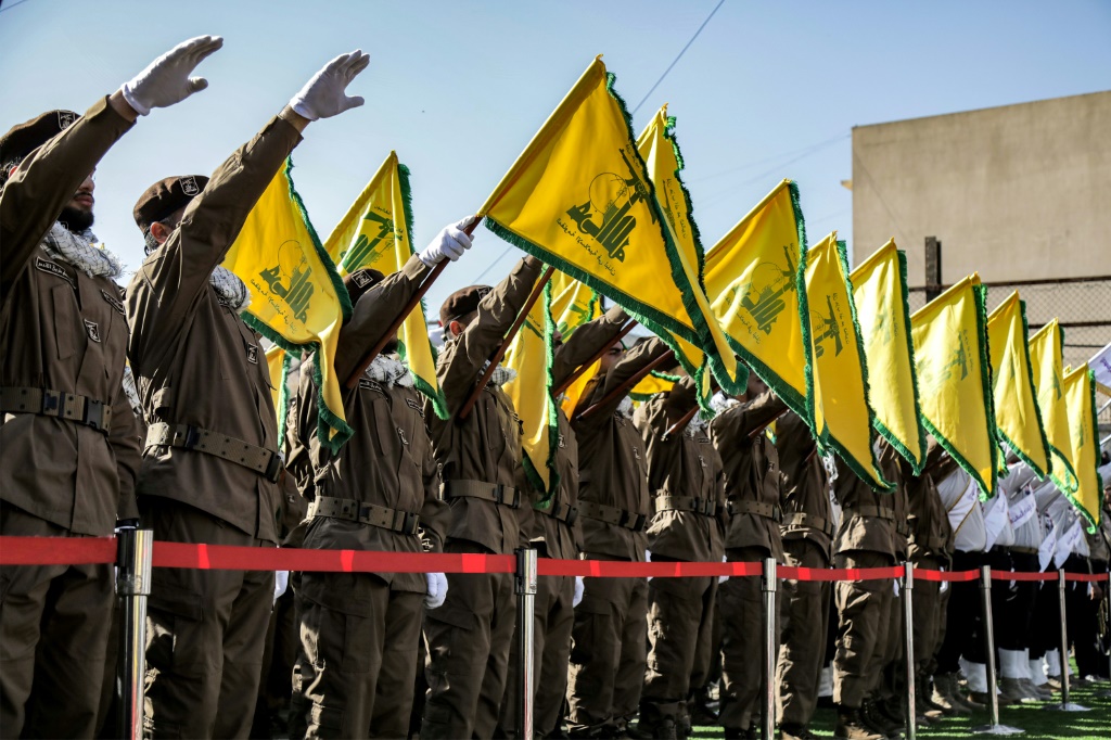 عناصر من حزب الله يؤدون التحية ويرفعون رايات الحزب خلال جنازة رفيقين قتلا بضربة إسرائيلية في الشهابية بجنوب لبنان في 17 نسيان/أبريل 2024 (أ ف ب)   