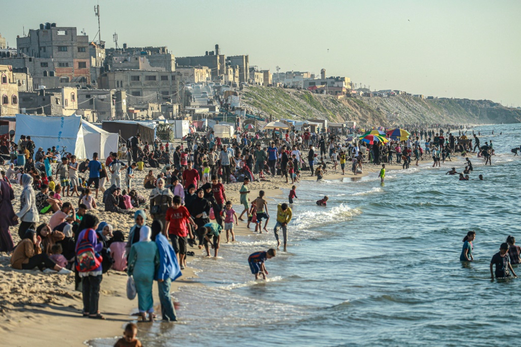  فلسطينيون يهربون من حر خيم النزوح إلى البحر في دير البلح وسط قطاع غزة في 17 نيسان/أبريل 2024 (أ ف ب)