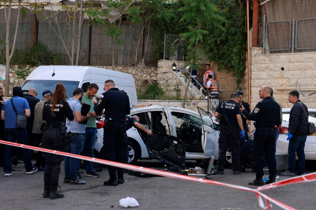 عناصر من الشرطة الإسرائيلية يتفحصون سيارة في موقع عملية دهس في القدس في 22 نيسان/أبريل 2024 (ا ف ب)
